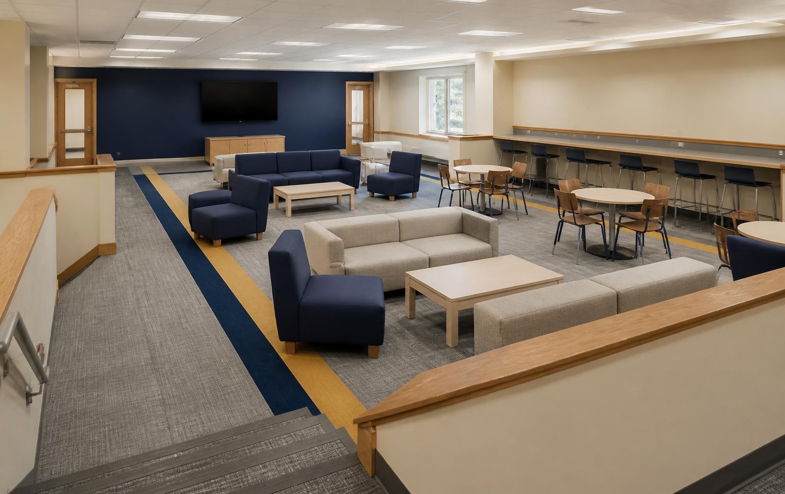 Overview of the Pit refreshed with greige carpet tile and navy and gold accent stripes, quickship modular lounge seating and a perimeter counter