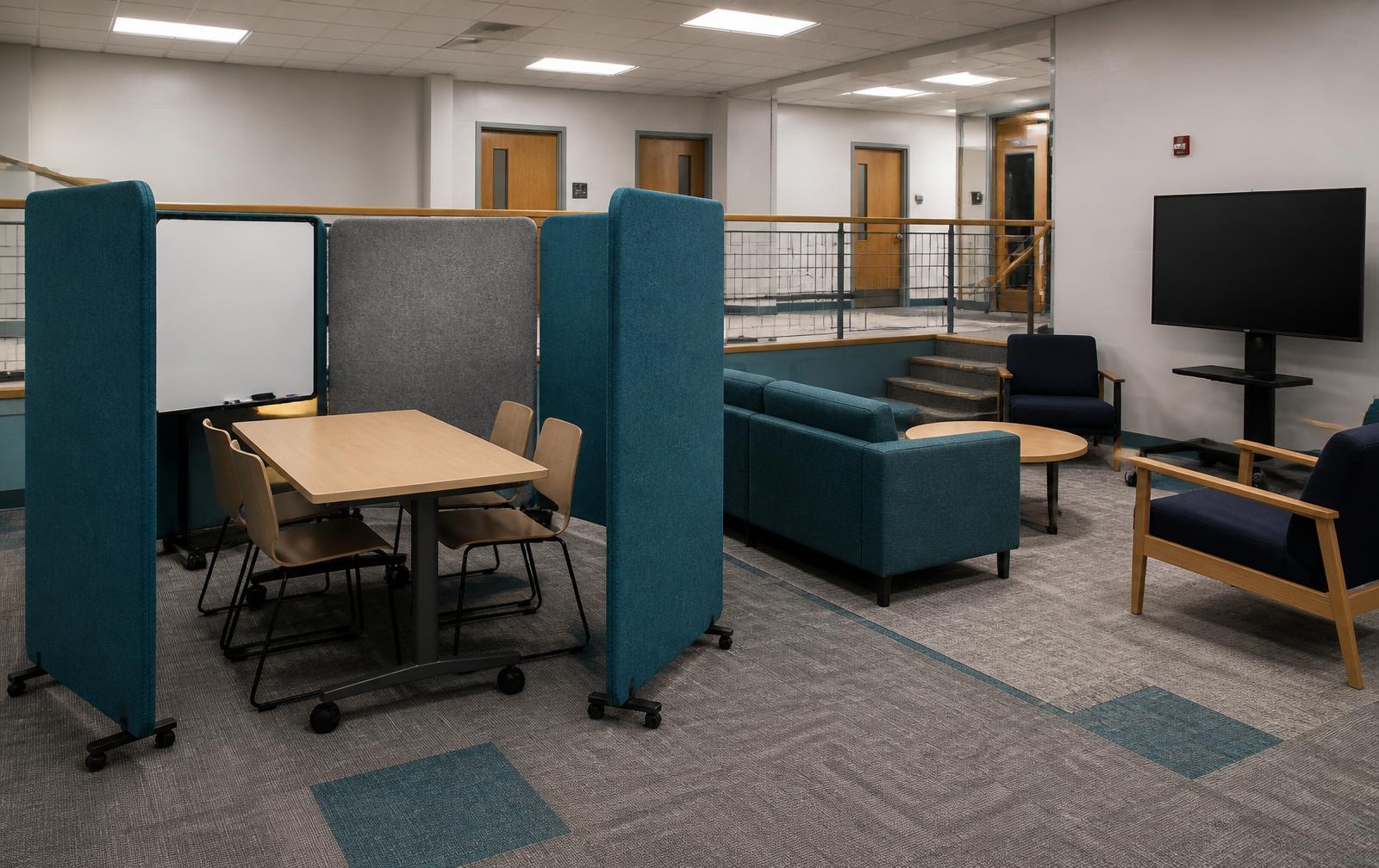 Mobile felt screen study pod with whiteboard beside teal modular sofas and a rolling display